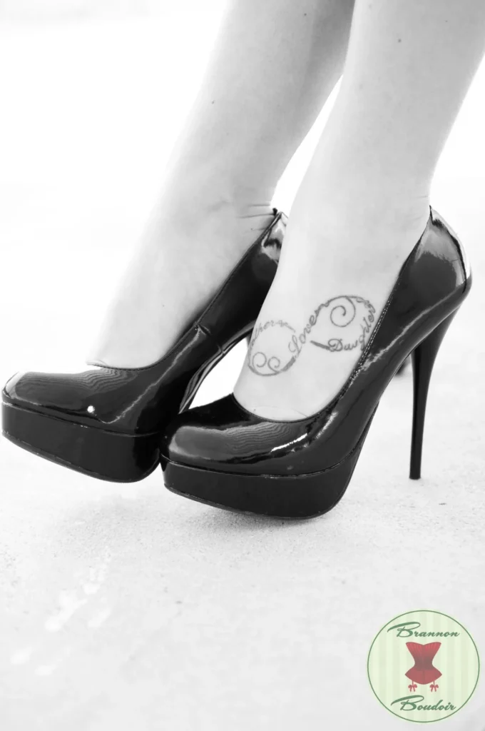 Monochrome detail of heels and an ankle tattoo