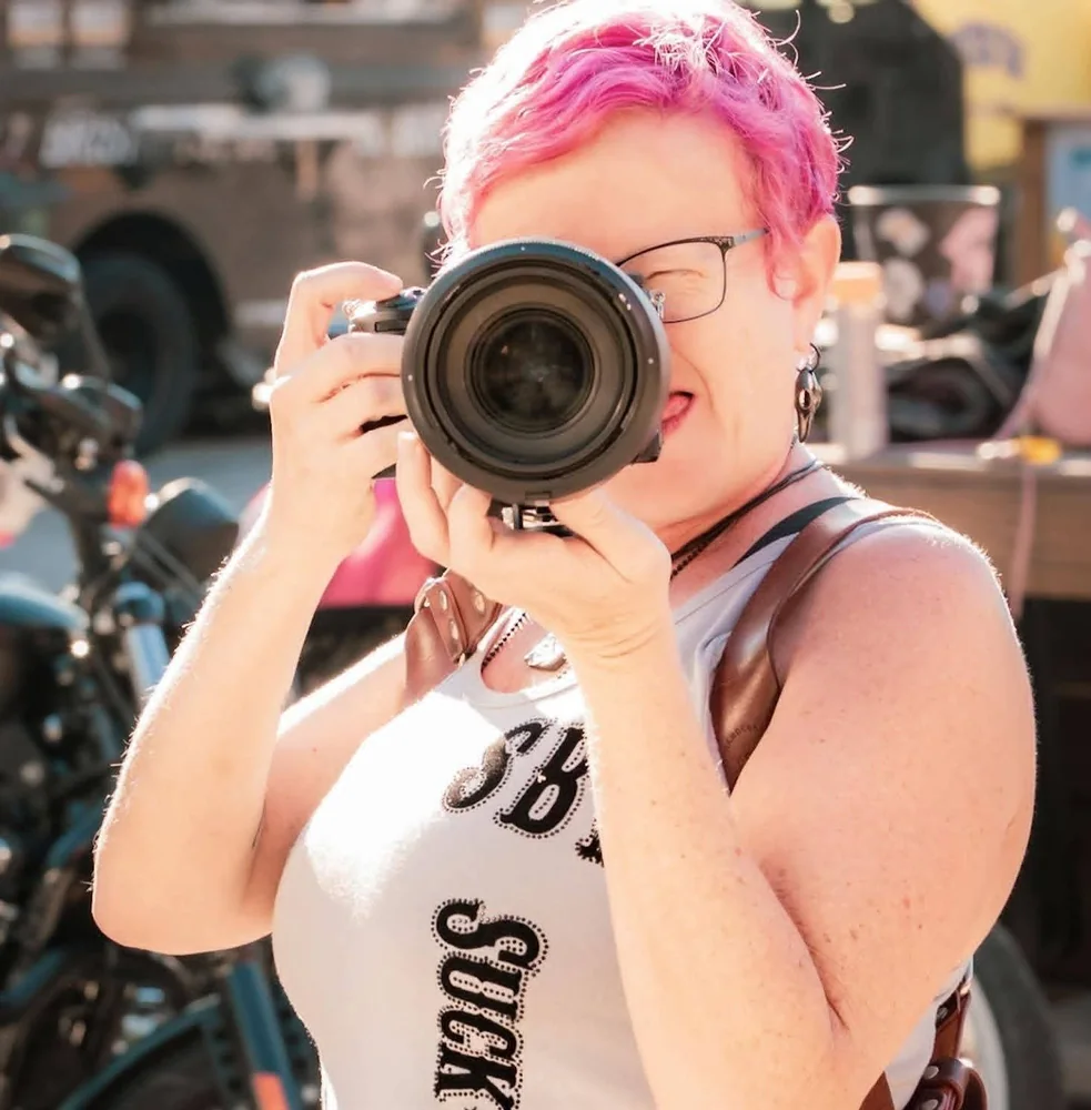 Casey Brannon with pink hair holding her camera