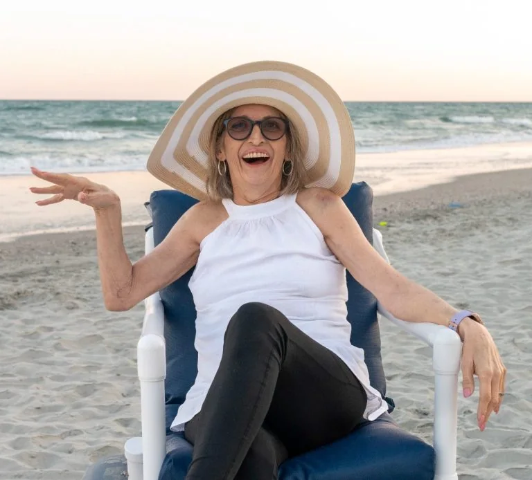 Woman smiling on the beach in a sun hat