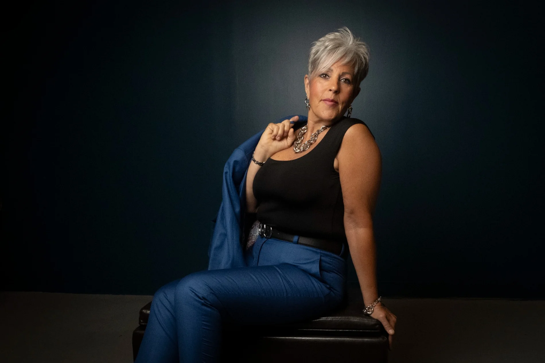 Seated studio portrait in blue against a dark background