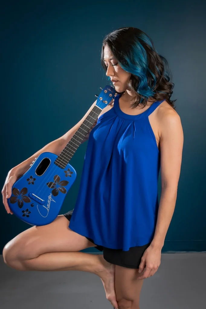 Studio portrait in blue holding a guitar