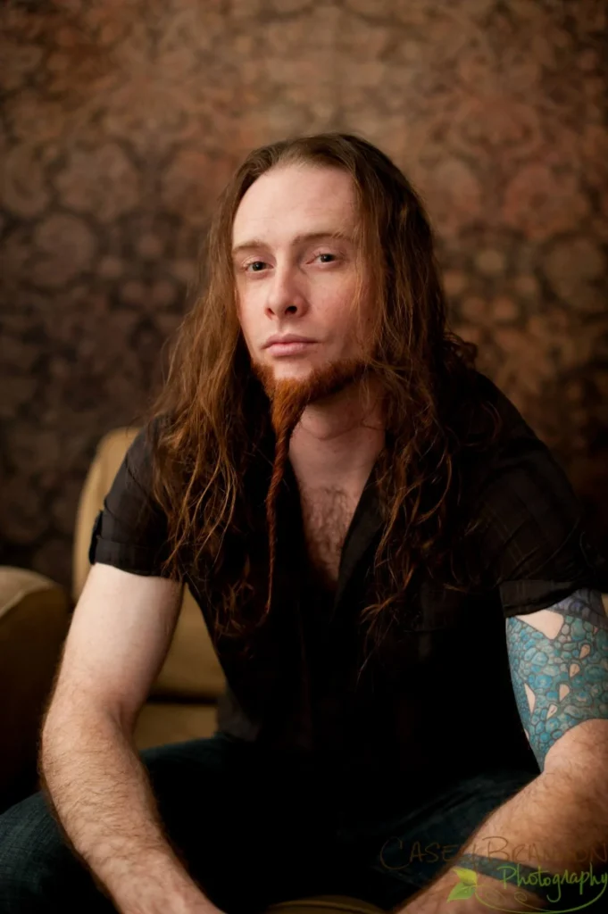 Portrait of a man against a warm patterned backdrop