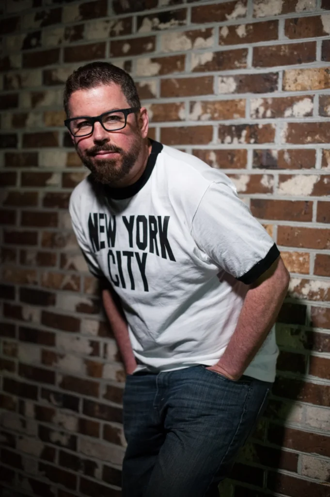 Portrait beside a brick wall wearing a graphic shirt
