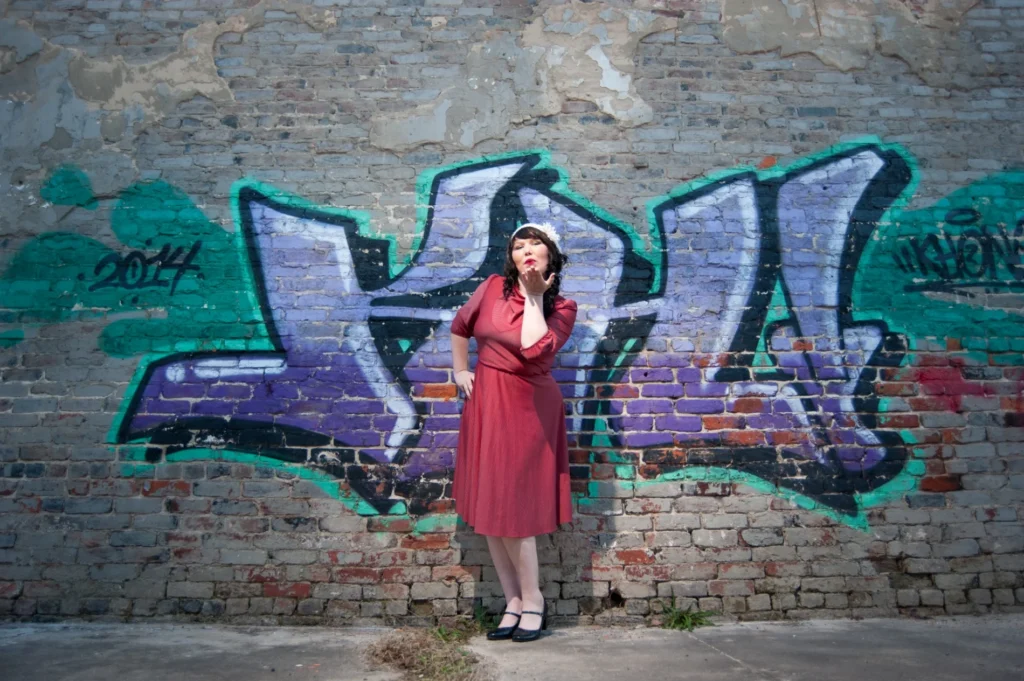 Senior portrait in a red dress beside a graffiti wall