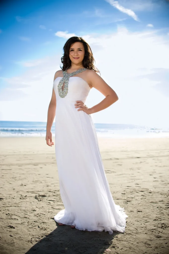 Senior portrait in a white gown on the beach
