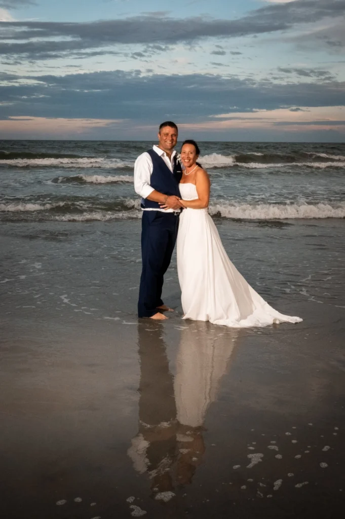 Wedding couple reflected in the wet sand at the ocean