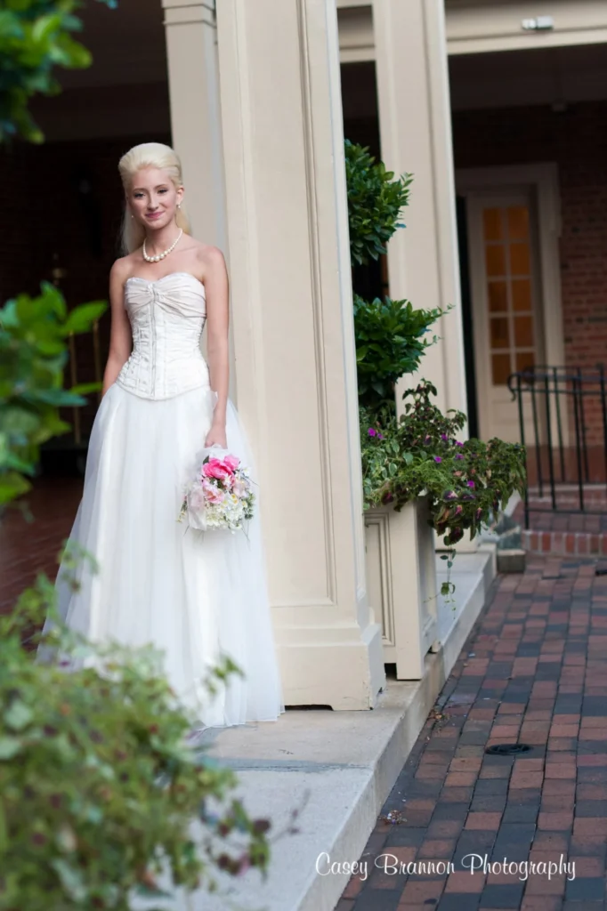Bride standing beside a white column with her bouquet