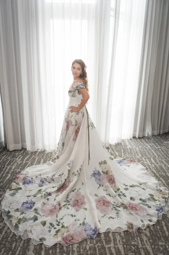 Bride beside a window with her floral train spread out