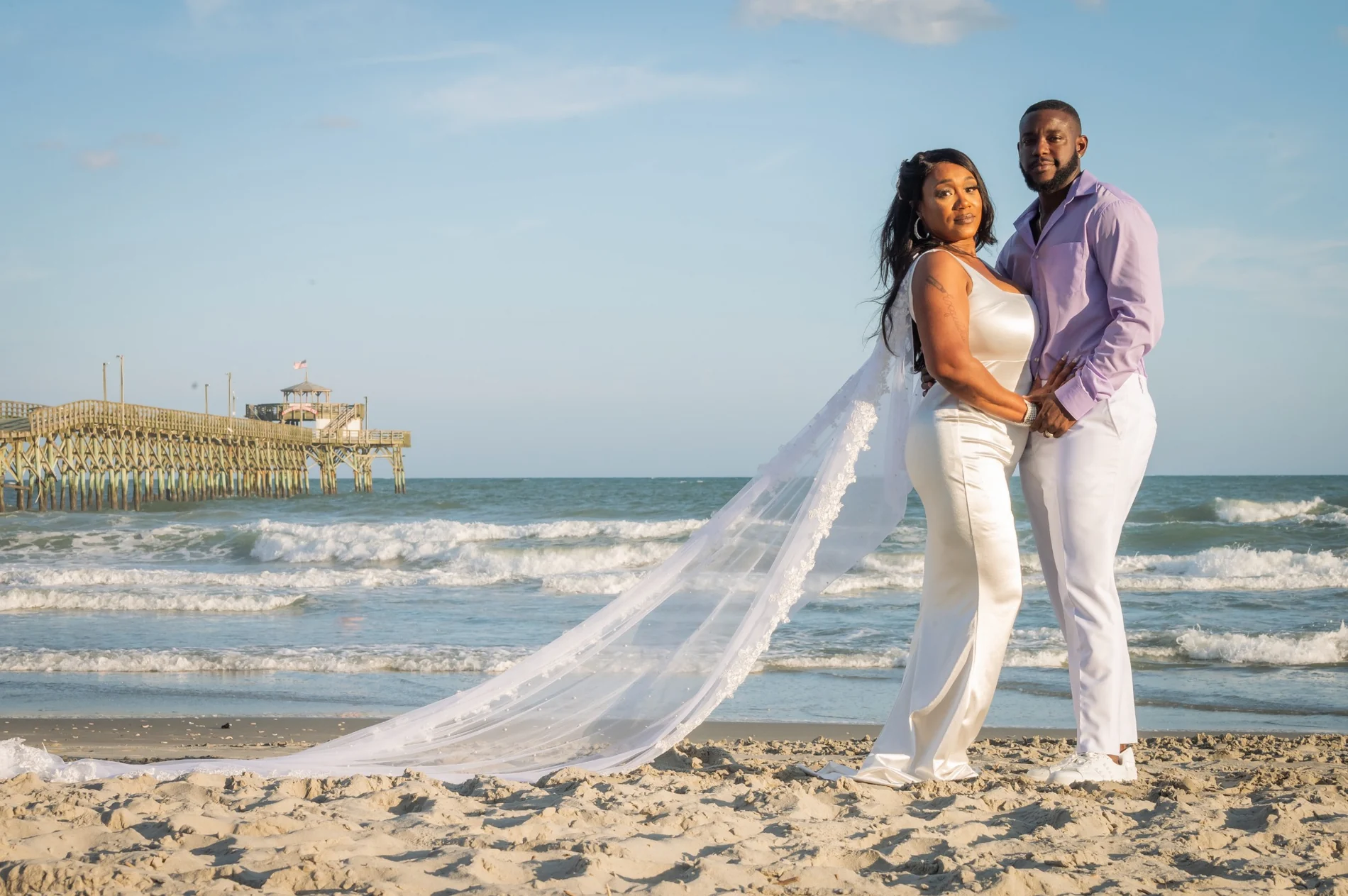 Wedding couple on the beach with a long flowing veil
