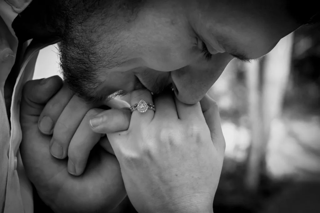 Groom kissing the bride&rsquo;s hand in a monochrome close portrait