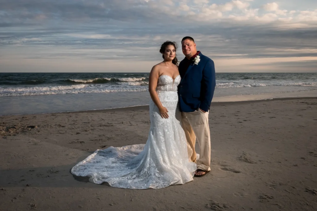 Newlyweds together on the beach beneath an evening sky