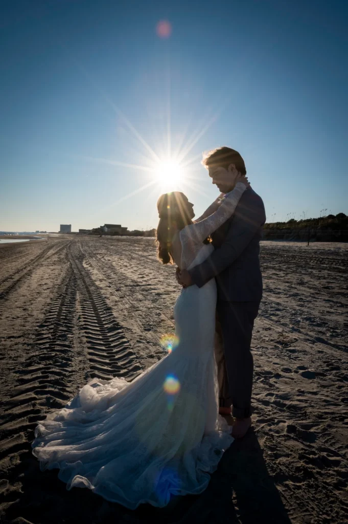 Wedding couple silhouetted against the sun on a sandy path