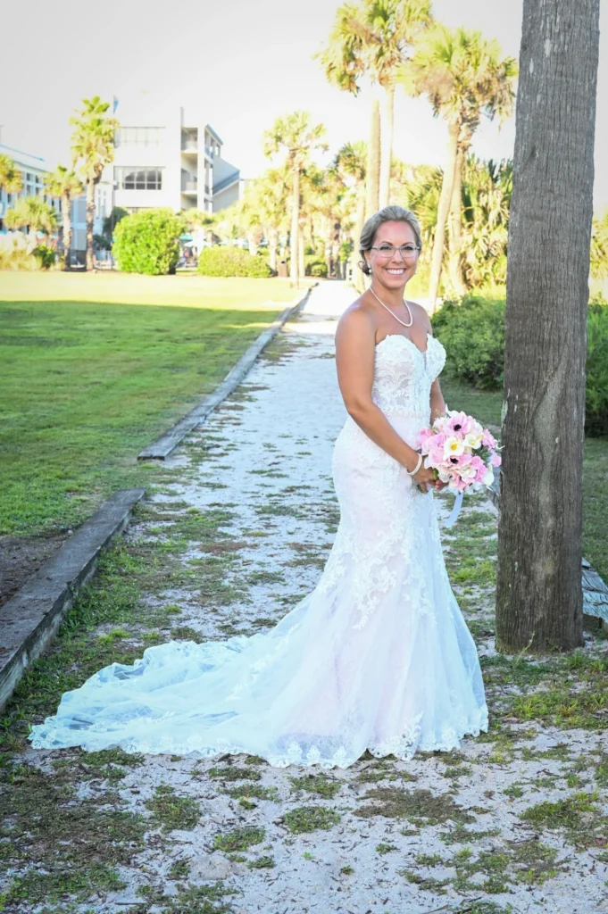 Bride seated near palm trees in her wedding gown