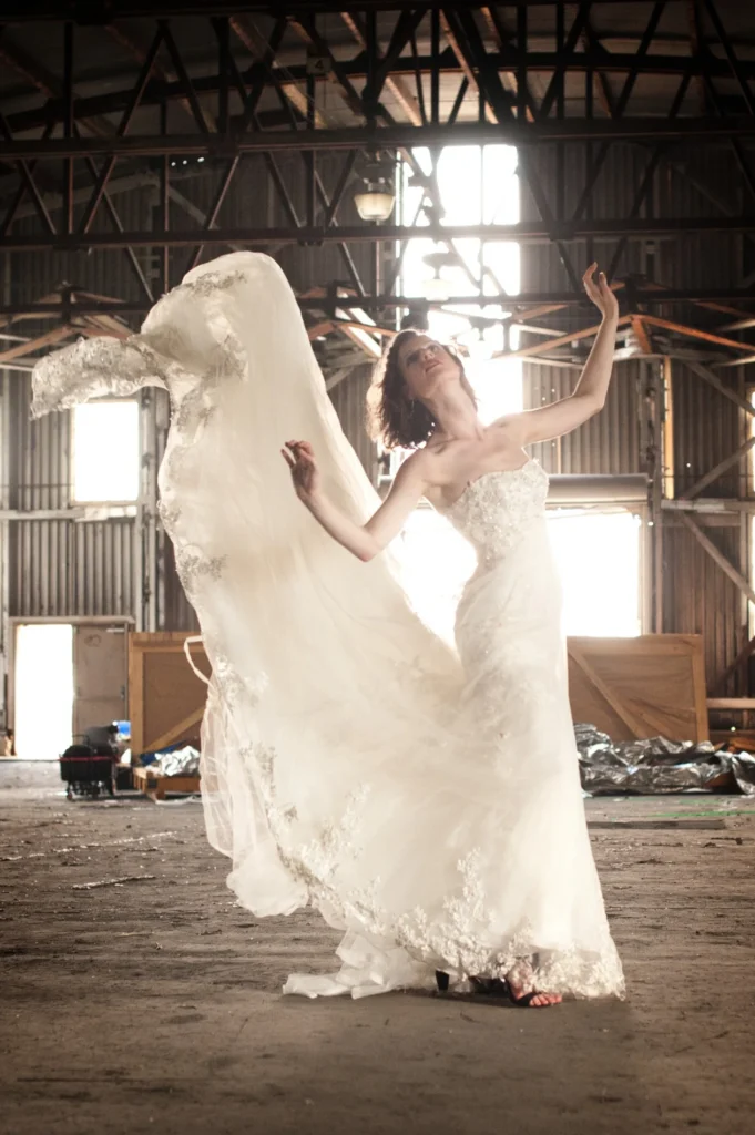 Bride lifting her flowing gown inside a rustic building