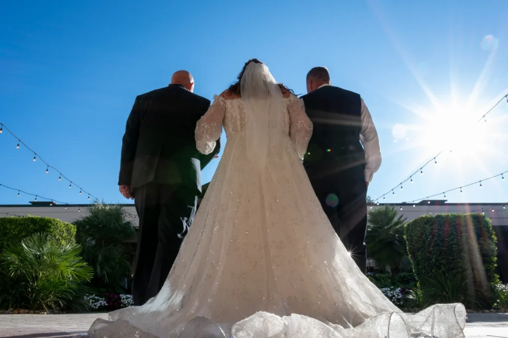 Bride walking with two companions toward the sunlight