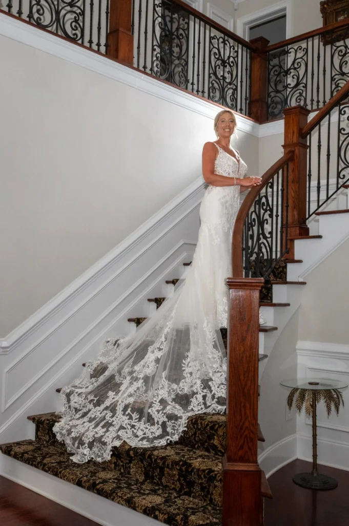 Bride beside a staircase with a long lace train