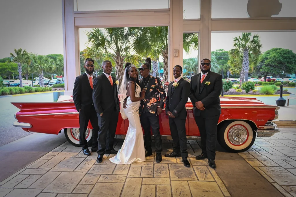 Wedding party gathered beside a vintage car
