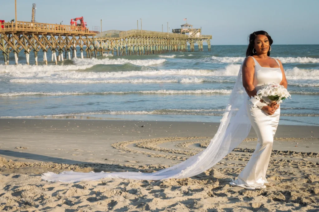 Bride on the beach with her veil flowing toward the pier
