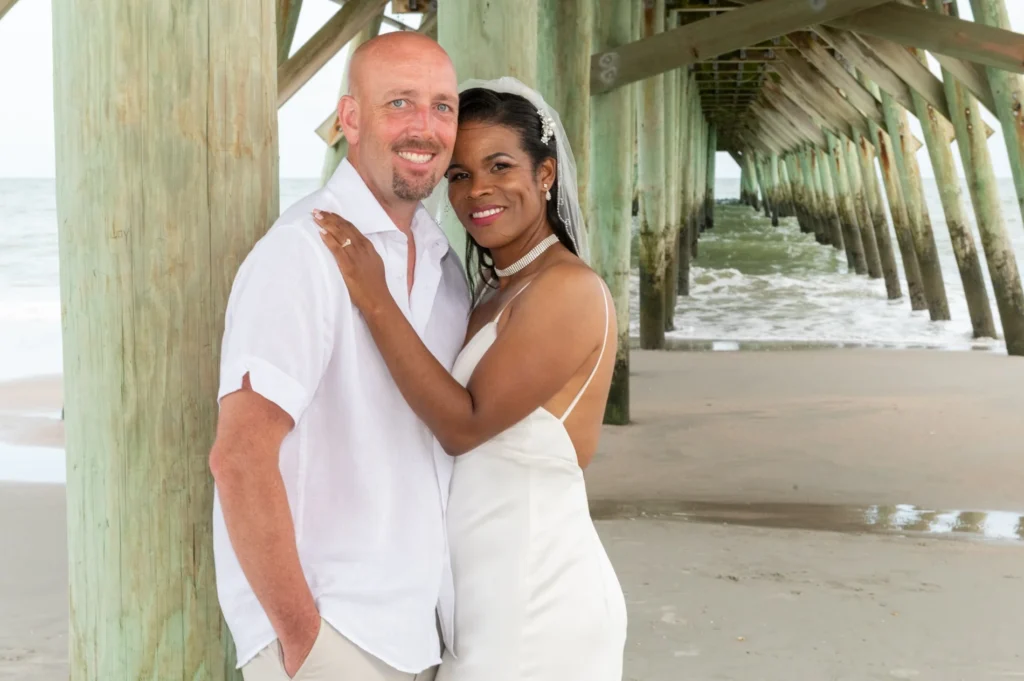 Wedding couple embracing beneath a wooden pier
