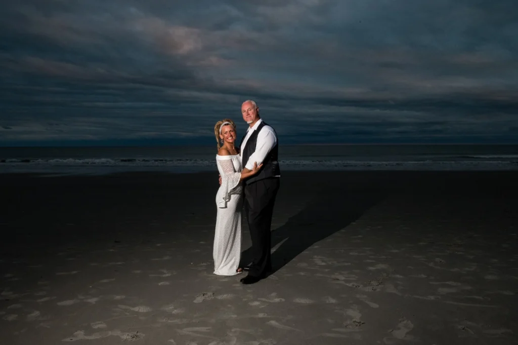 Wedding couple on the beach beneath a dramatic evening sky