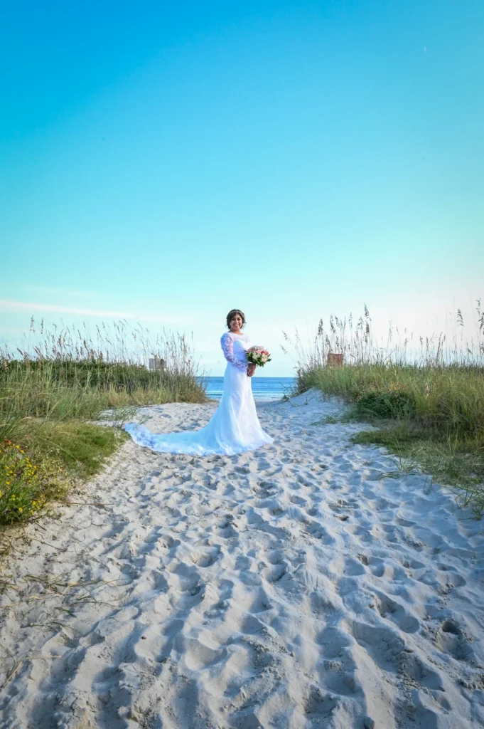 Bride standing on a sandy path between beach dunes