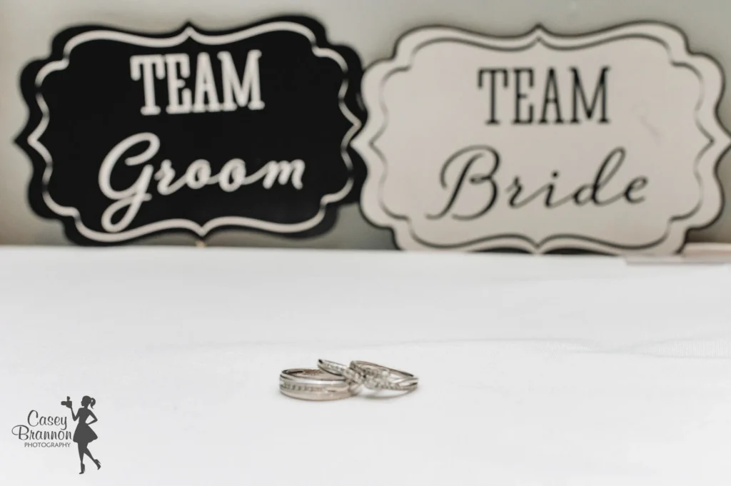 Wedding rings displayed beside Team Groom and Team Bride signs