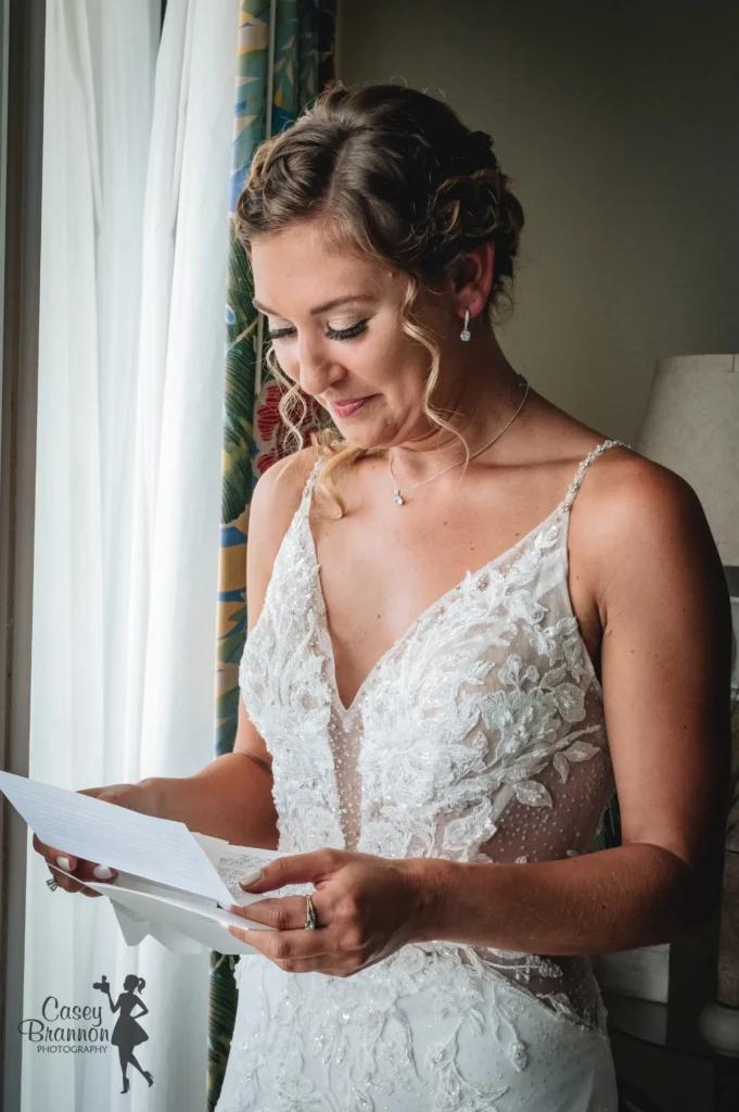 Bride reading a letter beside a window