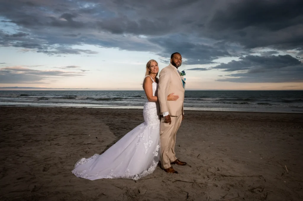 Newlyweds standing together on the beach at sunset